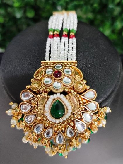 A beautiful maang tikka with a traditional design, featuring kundan work and colorful stones.
