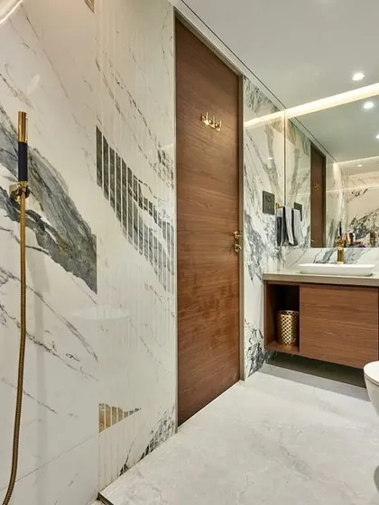 This bathroom showcases our expertise in working with book-matched marble. The dramatic veining of the stone flows across the walls, complemented by gold fixtures and a warm wood vanity for a sophisticated look.