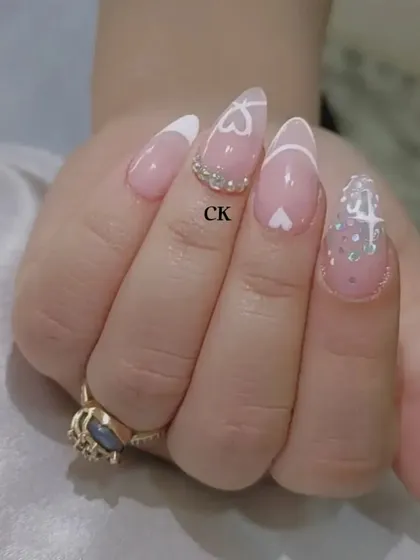 A close-up of the heart-themed French manicure, showing the fine line work and the placement of the rhinestones.