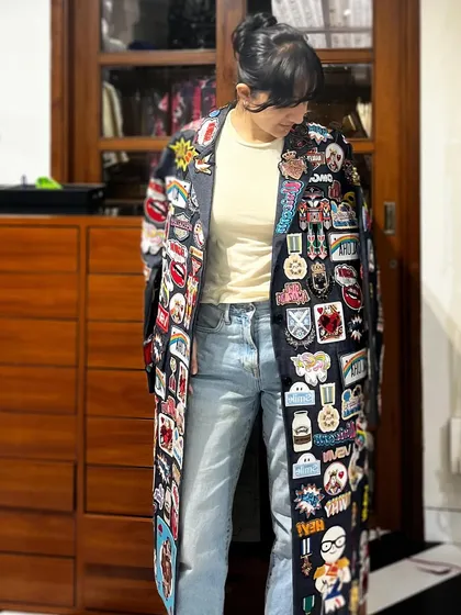 This floor-length trench coat is a canvas of stories, covered in a dense collage of custom patches and beadwork. It’s a maximalist piece that showcases my love for detailed, time-intensive embellishment.