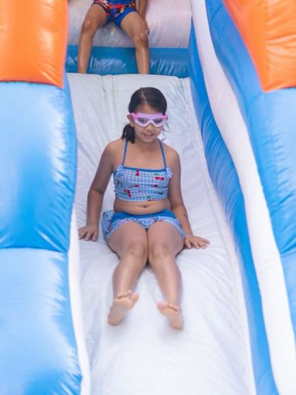 Whee! A guest has a blast coming down the water slide on the inflatable bouncy. Safety and fun go hand in hand at my parties.