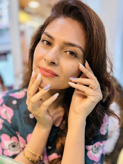 Beauty is in the details. This client is glowing after her salon session, with beautifully styled hair and glitter-dipped nails that add a touch of sparkle.