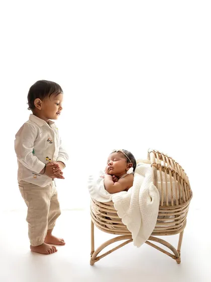 A precious moment as a big brother stands and watches over his new baby sister sleeping in her bassinet.