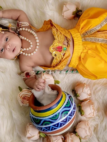 Our little Krishna resting with his matki (pot) of butter. This top-down view on a bed of roses creates a divine and adorable portrait for your baby's first festival.
