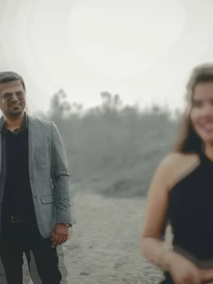 A creative pre-wedding shot using focus to draw attention to the groom while the bride is softly blurred in the foreground, telling a story of perspective.