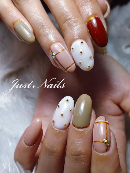 An elegant and modern design with a mix of neutral tones. This set features white nails with gold studs, beige nails with gold line art, and a solid reddish-brown accent.