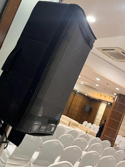 A powerful QSC K12.2 series speaker, strategically placed to provide even and clear sound coverage across the entire hall. This ensures everyone in the audience has a great listening experience.