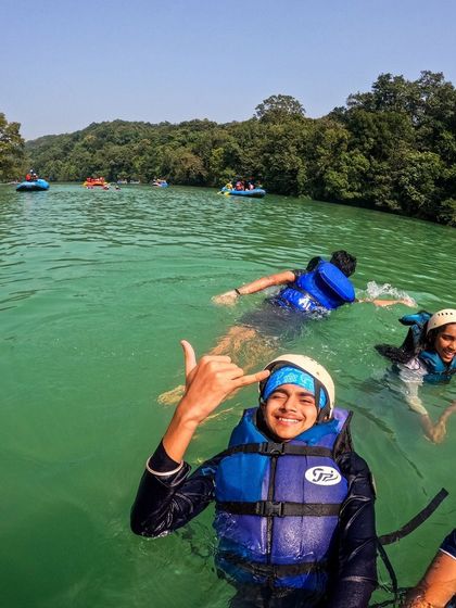 A trekker enjoying a swim in the clear green waters of the Kali river.