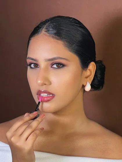 Showing a touch-up moment on set. The glossy lip adds a fresh, modern feel to this otherwise classic and clean makeup look.