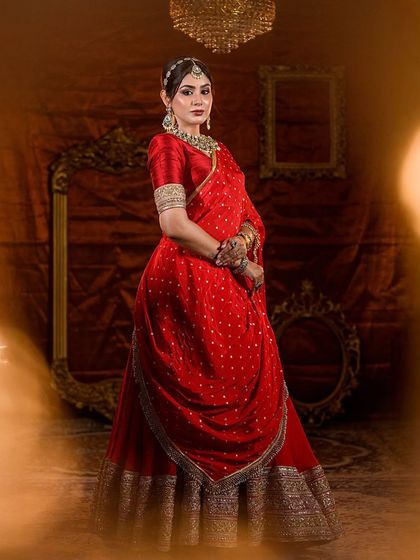A full shot of a bride in a red lehenga, showcasing a classic bridal look with a modern draping style.