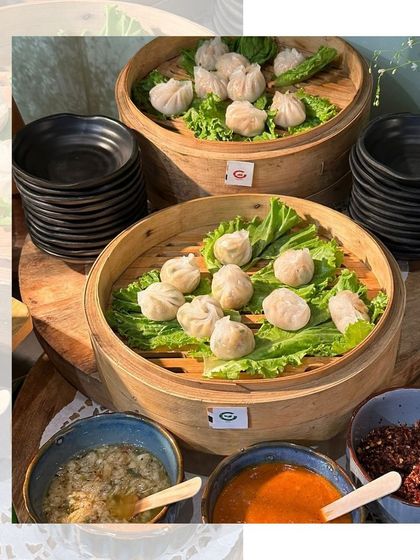 A live dim sum station with multiple bamboo steamers, offering guests a variety of freshly steamed dumplings with an array of authentic sauces.