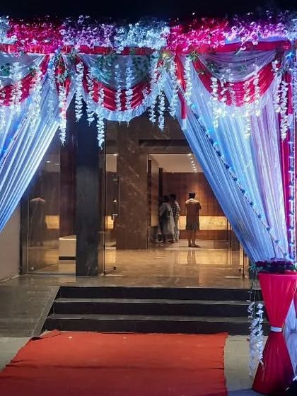 A grand entrance designed for the Pyramid Element venue. The red carpet leads guests through a beautifully draped archway with hanging floral elements and integrated lighting, setting a luxurious tone for the event.