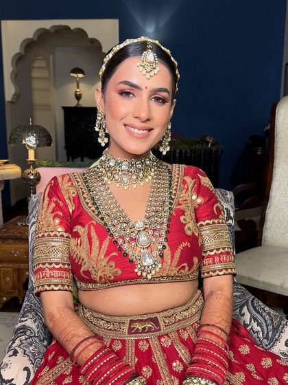 The happy bride, ready for her destination wedding in Jaipur. Her traditional red Sabyasachi lehenga is perfectly complemented by the classic floral bun hairstyle.