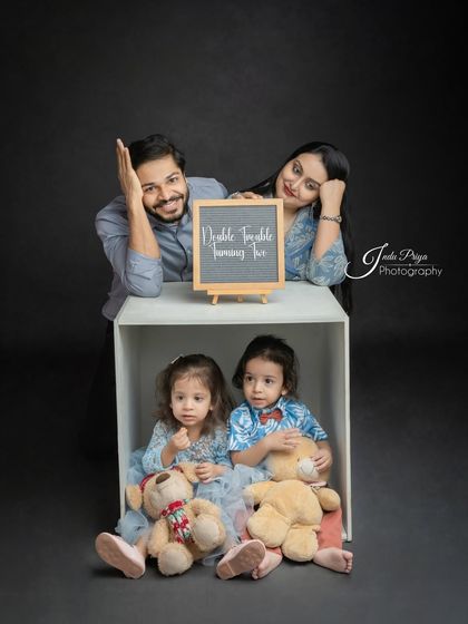'Double Trouble Turning Two!' This fun shot uses a chalkboard sign to add a playful message to the family portrait, celebrating the twins' milestone.