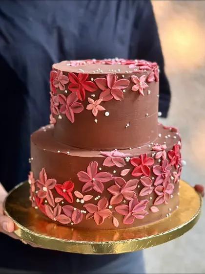 A closer look at the delicate, hand-piped buttercream flowers on our two-tiered chocolate wedding cake. Each petal is crafted with care to create a stunning, edible work of art.