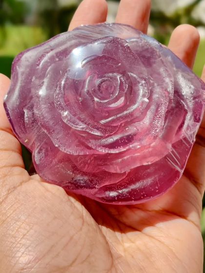 A purple transparent rose soap. The clarity of the base allows the light to shine through, highlighting the intricate details of the rose mold.