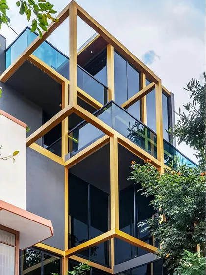 A low-angle view of the 'SOL' residence's facade, where the interlocking golden frame creates a powerful architectural statement. The design plays with solid and void, creating cantilevered balconies and shaded glass surfaces that give the building a light, dynamic quality.
