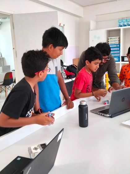 Collaboration is at the heart of our programs. A team of students huddles around a laptop, working together to write the code that will bring their robot to life.