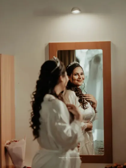 The bride getting ready, looking at her reflection with a happy smile, anticipating the moment she says 'I do'.
