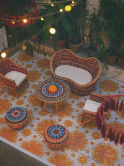 A cozy, low seating lounge for a Mehendi. We used a printed rug and colorful woven furniture to create a relaxed, boho-inspired corner for guests to chat and get their henna done.