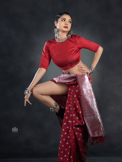 A full-body shot that captures the unique silhouette of the modern saree drape combined with boots. This image is perfect for an editorial that explores contemporary Indian fashion.