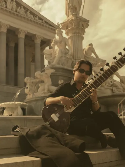 Playing my sitar in Vienna, with the city's grand architecture in the background. Taking my music to different parts of the world is a constant source of inspiration.