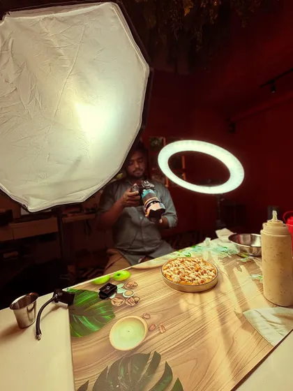 A wider view of my food photography setup. You can see the use of a large softbox and a ring light to create balanced, professional lighting for the product shot.