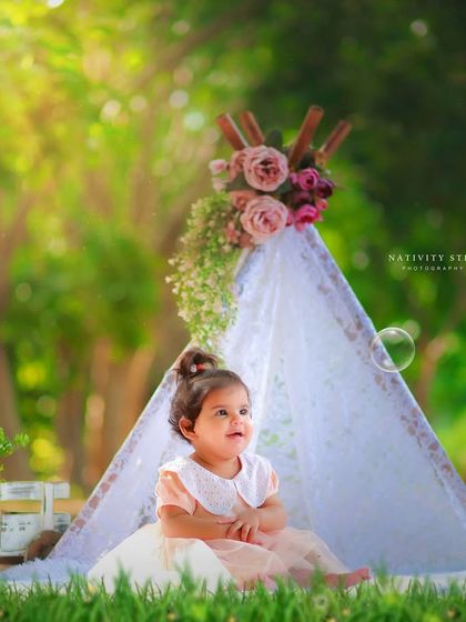 A moment of wonder during an outdoor first birthday session. The bubbles add a touch of magic to this portrait, set against our popular floral teepee backdrop.