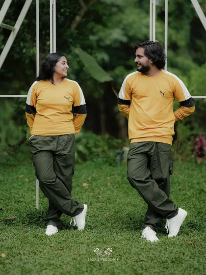 The couple leaning against a white structure, their matching outfits and mirrored poses creating a fun, symmetrical shot.