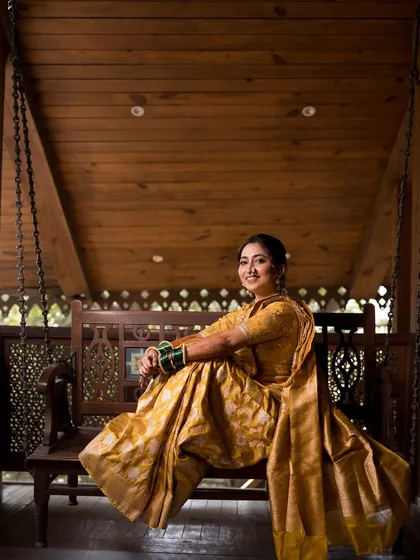 A full view of the bride on the swing, looking regal against the wooden architecture.