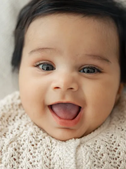 The happiest, most wide-eyed smile. This close-up portrait captures the pure joy and innocence of a baby, a perfect memory from a milestone session.
