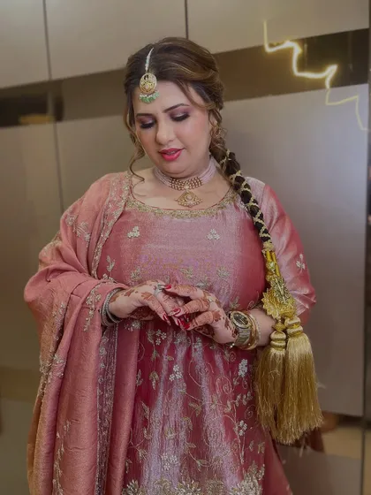 A close-up of her holding the parandi, showing the intricate henna and the soft, glowing makeup.