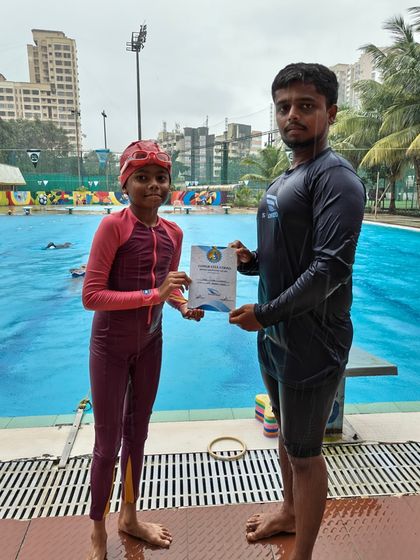 This young swimmer has officially leveled up. Here she is with her coach and her well-earned certificate of achievement.