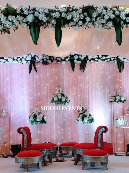 We created this elegant mandap with a canopy of delicate white florals and hanging greenery. The bold red chairs provide a central focus, symbolizing love and tradition.