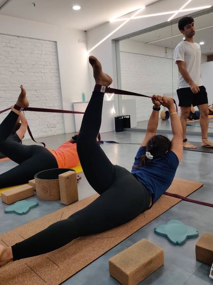 Using straps to go deeper. A student in our backbend workshop explores a reclining leg stretch, using a strap to safely increase flexibility in her hamstrings and hips.