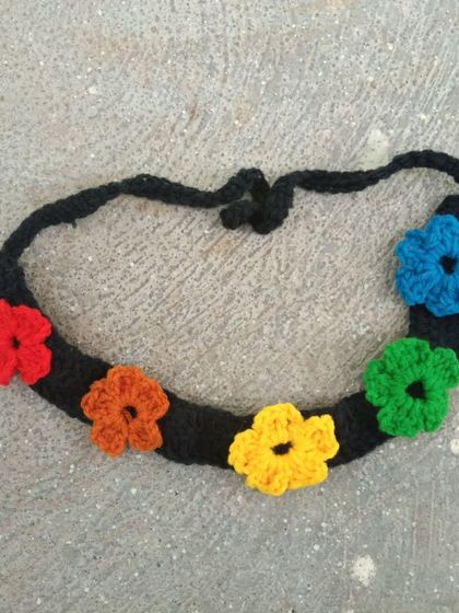 A vibrant rainbow flower headband. This piece features six colorful flowers on a black band, creating a beautiful contrast. It’s a cheerful accessory for any occasion.