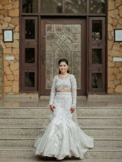 A full-length shot of the bride in her stunning white gown, standing confidently on the steps of a beautiful stone building.
