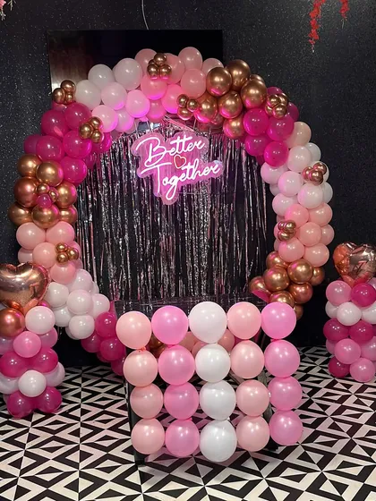 A 'Better Together' setup with a pink and gold theme. This balloon arch with a silver foil curtain is perfect for engagements, anniversaries, or bridal showers.