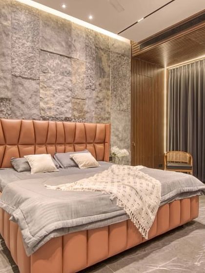 A bedroom featuring a textured stone accent wall and a hidden door seamlessly integrated into a fluted wood panel. This demonstrates our skill in creating cohesive and surprising design elements.