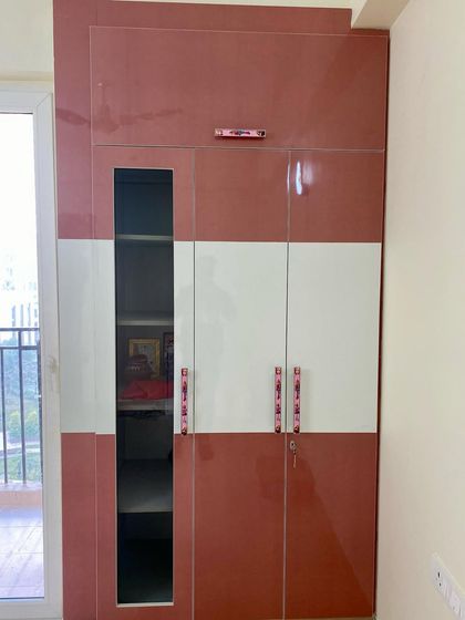 A closer look at the kids' room wardrobe, showing the combination of pink and white high-gloss laminate and stylish handles.