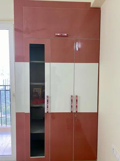 A closer look at the kids' room wardrobe, showing the combination of pink and white high-gloss laminate and stylish handles.