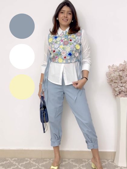 A playful and creative look. The embroidered floral vest adds a pop of color and texture to the simple white shirt and light blue trousers.