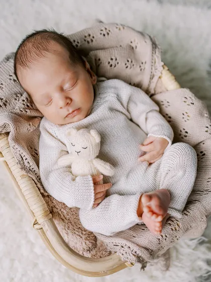Another angle of a sweet, sleeping newborn in a cozy knit outfit, showing the different poses we can achieve even with slightly older newborns.