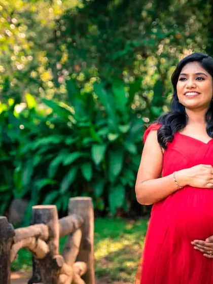 A simple, elegant portrait of the mom-to-be in a red dress, bathed in the soft light of the garden.