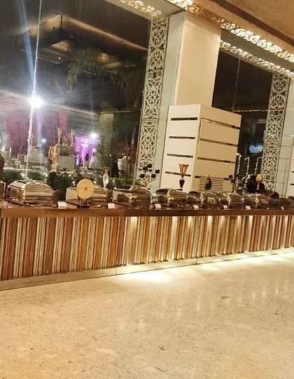 A wide view of a modern and sophisticated indoor buffet line. The sleek, wood-paneled counters and warm lighting create a luxurious atmosphere for corporate events and large gatherings.