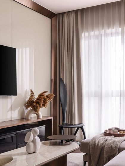 The high-gloss TV panel reflects the light, making the space feel brighter and more expansive. The sculptural chair adds an artistic touch to this cozy corner.