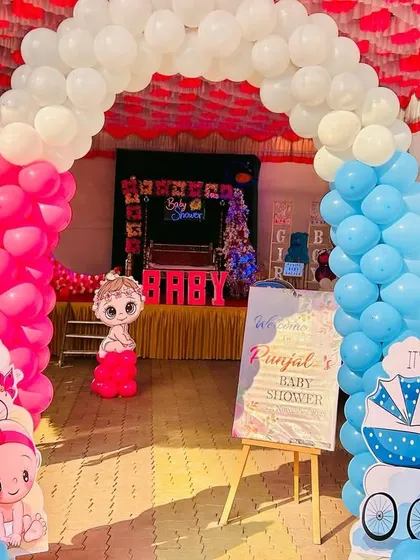 A gender reveal themed entrance for a baby shower, with pink and blue balloon arches and 'It's a Girl' and 'It's a Boy' cutouts.