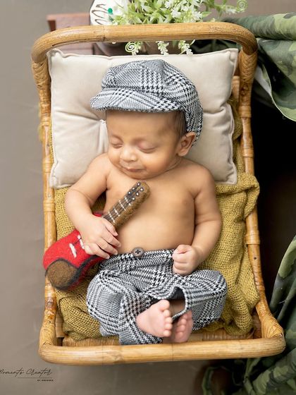 A little musician dreaming of his first song. This newborn, in a charming plaid outfit, sleeps peacefully with his miniature guitar.
