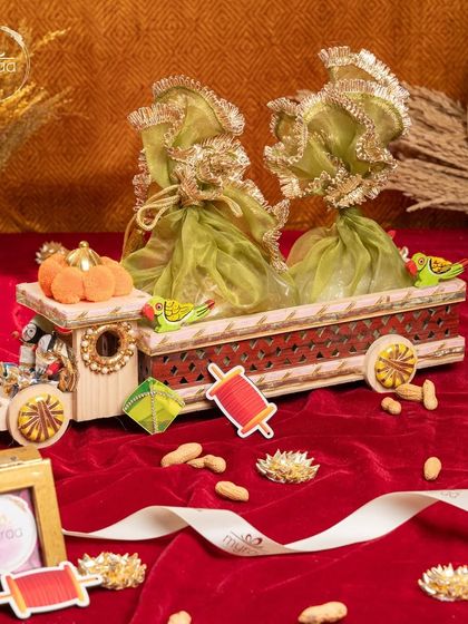 A whimsical Lohri gift featuring a decorative wooden train cart filled with festive green potlis. It's a playful and charming way to present your Lohri treats.