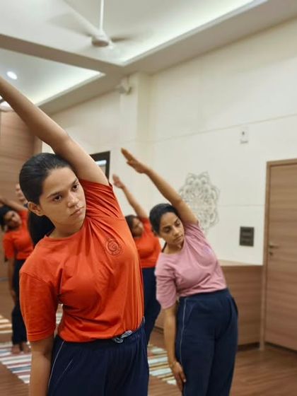 Students engage in a synchronized side stretch, a fundamental asana for improving spinal flexibility and posture. Our classes methodically move through postures to warm up and prepare the body safely.